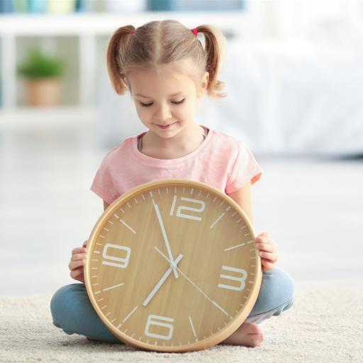 Kind hält eine große Uhr in den Händen Der Tagesablauf in der KiTa im Haus der Kinder im Spessart